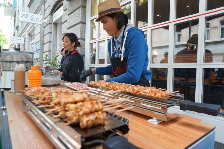 Rio Vanory saat beraksi membakar sate ayam di depan sebuah restoran makanan Asia di Zurich, Swiss.