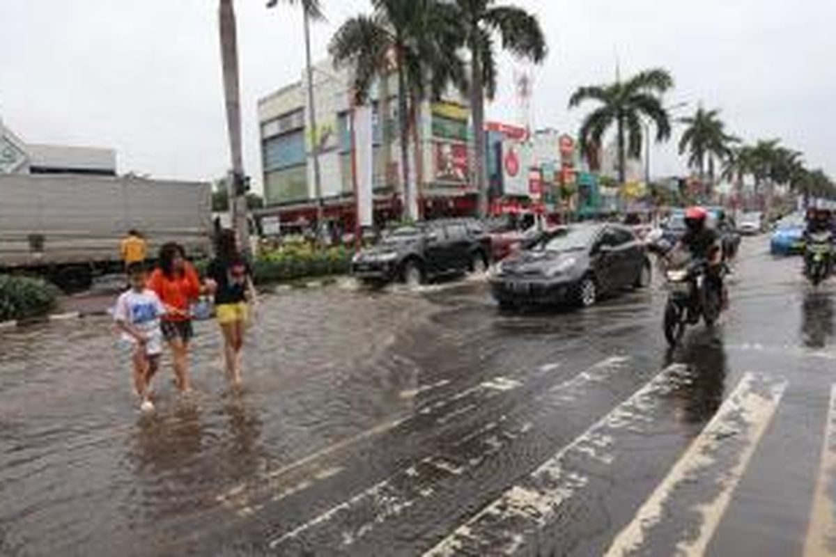 Warga melintasi genangan banjir di Jalan boulevard, Kelapa Gading  Jakarta Utara, Jumat (17/1/2014). Hujan lebat mengguyur Jakarta sejak pagi, membuat sejumlah jalanan Ibukota tergenang. Warta Kota/angga bhagya nugraha