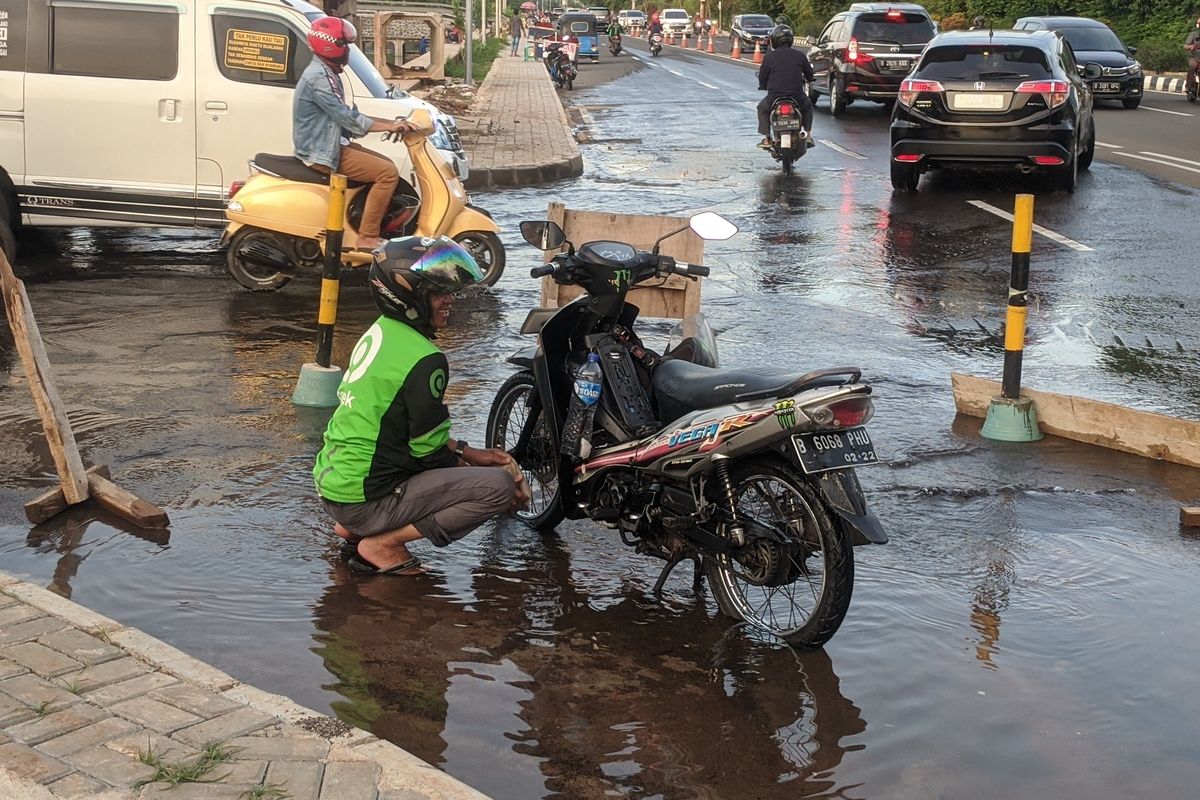 warga bergantian memanfaatkan semburan air di Jalan Boulevard BGR Perintis Kemerdekaan, Kelapa Gading Barat, Jakarta Utara, Selasa (21/1/2020)