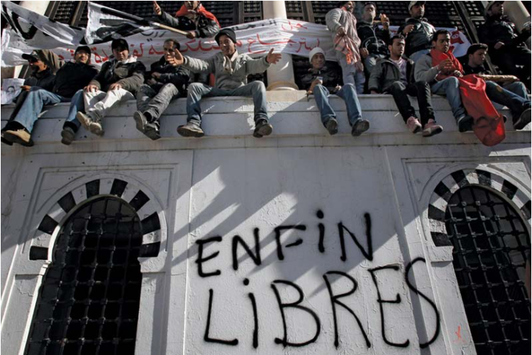 Revolusi Melati: Demonstran duduk di dinding yang bertuliskan Akhirnya Bebas. 