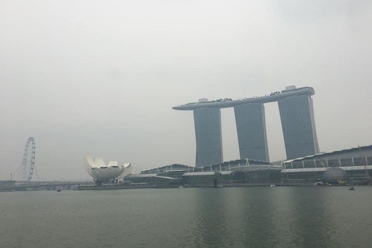 Kabut asap menyelimuti ikon pariwisata Singapura di distrik Marina Bay seperti Hotel Marina Bay Sands, Museum Seni dan Sains Singapura, dan kincir angin raksasa Singapore Flyer, Sabtu siang (14/9/2019) 