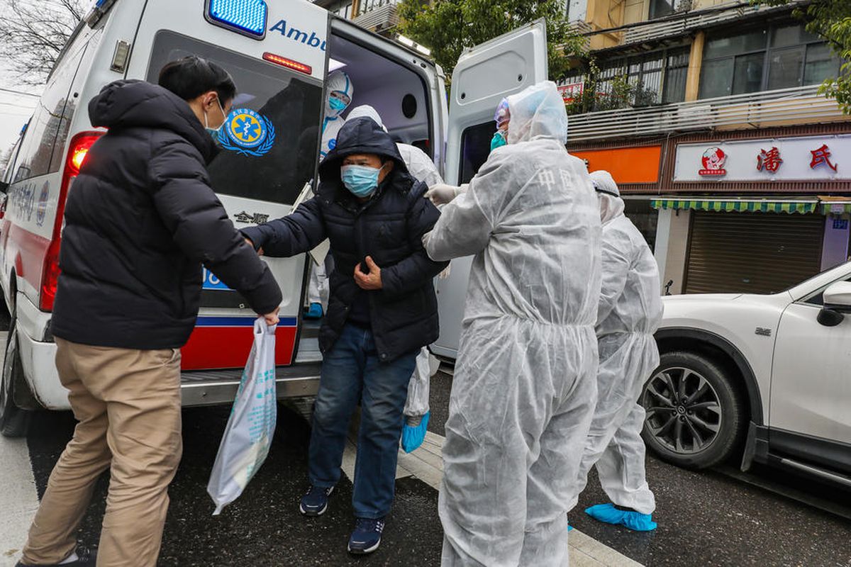 Petugas medis yang mengenakan pakaian pelindung membantu pasien turun dari ambulans di luar rumah sakit di Wuhan, Hubei, China, pada 26 Januari 2020. Penyebaran virus corona sejak Desember 2019 sudah membunuh lebih dari 300 orang di China.