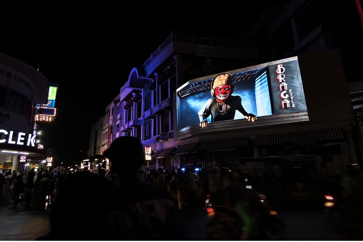 Penampilan Si Cepot dalam videotron di kawasan Braga, Bandung, Jawa Barat, menarik minat wisatawan yang tengah berlibur. 