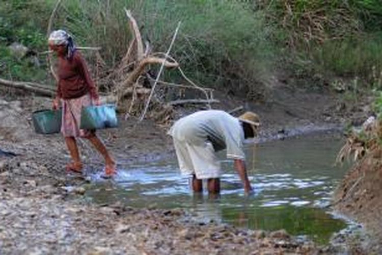 Warga Dusun Kabe'en Laok, Desa Bujur Barat, Kecamatan Batumarmar, Pamekasan, mengangkut air dari dalam sungai sisa-sisa banjir msuim hujan.