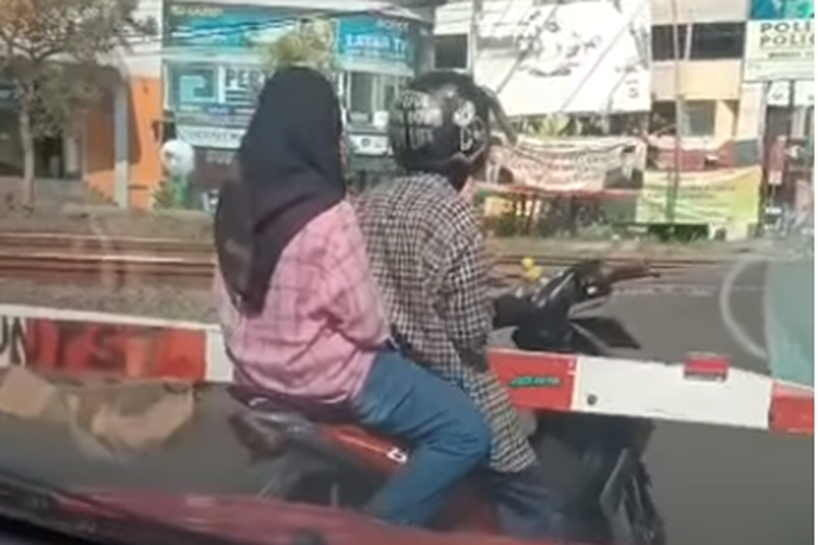 Tangkapan layar video yang memperlihatkan pengendara motor terjepit palang perlintasan kereta api di Karawang,