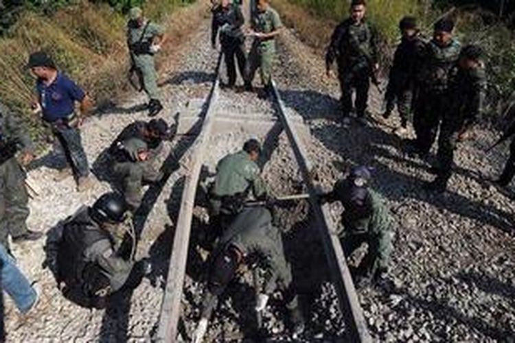 Anggota kepolisian memeriksa lokasi ledakan bom yang diduga ditanam di bawah rel kereta api oleh kelompok militan di Thailand selatan, Minggu (18/11/2012). Serangan itu menewaskan satu orang dan melukai 15 orang lainnya. 