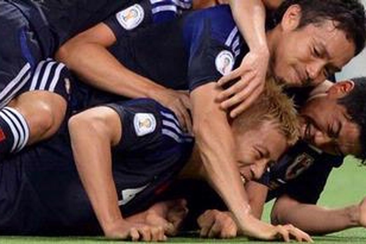 Gelandang Jepang, Keisuke Honda (bawah) dikerubuti rekan-rekannya,a termasuk Shinji Kagawa (kanan), usai dia mencetak gol penalti ke gawang Australia, Selasa (4/6/2013), pada kualifikasi Piala Dunia zona Asia. Hasil imbang ini pastikan Jepang raih tiket putaran final Piala Dunia 2014.