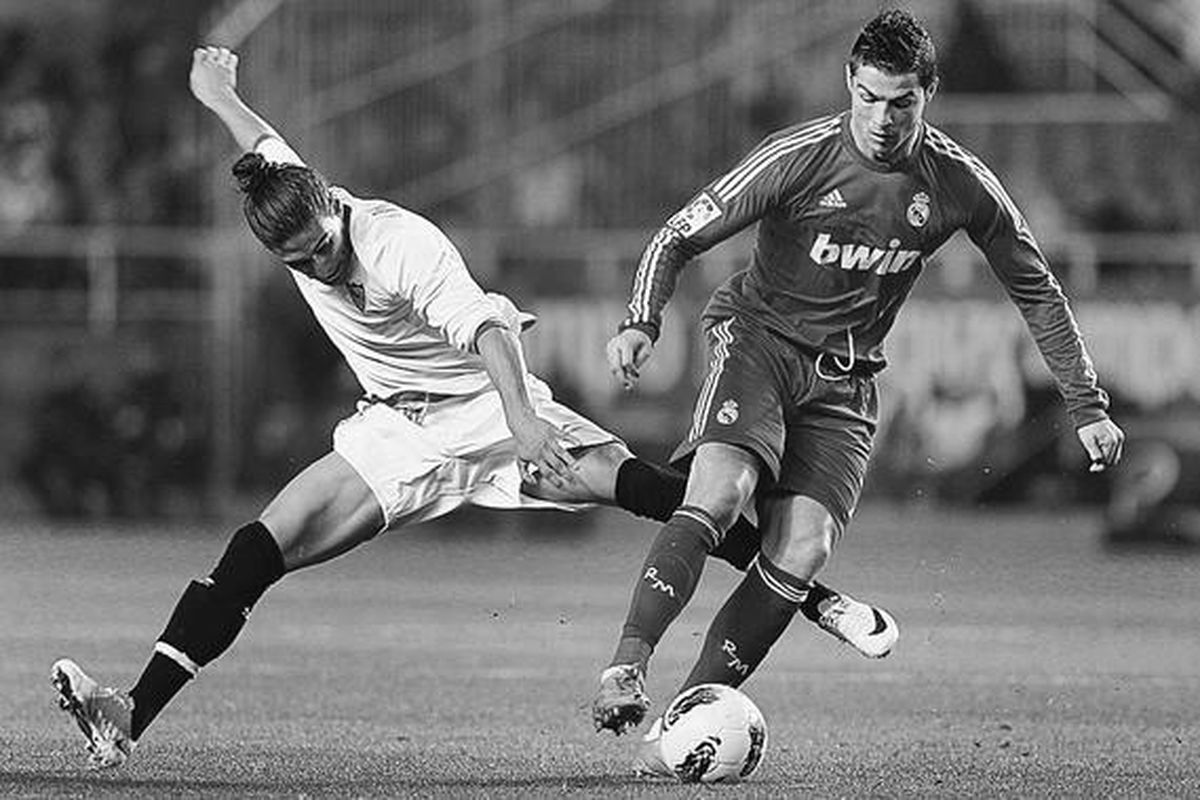 Penyerang Real Madrid asal Portugal, Cristiano Ronaldo (kanan), berebut bola dengan pemain Sevilla, Martin Caceres (kiri), pada lanjutan laga Liga Spanyol di Stadion Ramon Sanchez Pizjuan, di Sevilla, Spanyol, Sabtu (17/12).