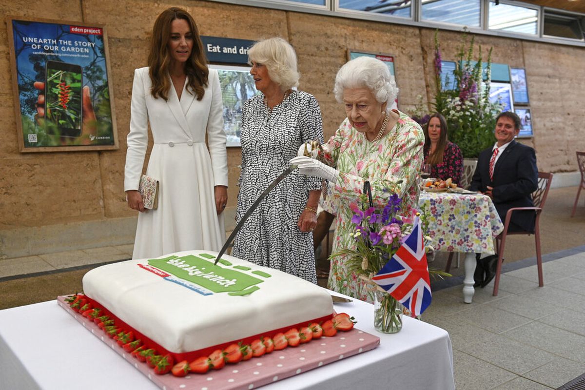 Ratu Inggris Elizabeth II (tengah), memotong kue didampingi Camilla, Duchess of Cornwall, dan Kate, Duchess of Cambridge, saat mereka menghadiri acara perayaan inisiatif 'The Big Lunch ', selama KTT G7 di Cornwall, Inggris, Jumat 11 Juni 2021.