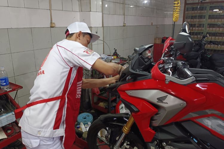 Mekanik Bengkel Resmi Honda sedang memperbaiki kelistrikan sepeda motor.