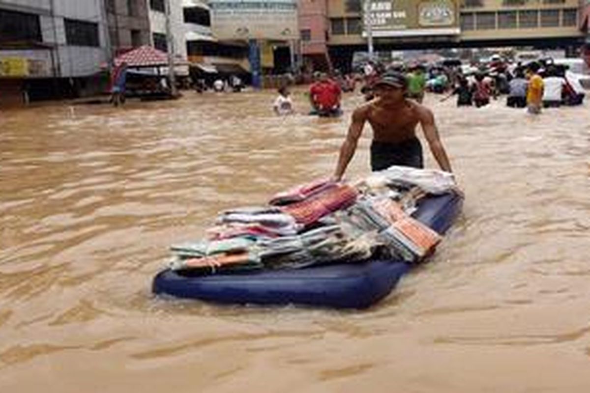 Seorang pedagang di pasar Cipulir menyelamatkan barang dagangannya yang terendam banjir dengan bantuan kasur, Sabtu (3/2/2007). Banjir yang melanda Jakarta melumpuhkan transportasi dan perekonomian di sebagian besar wilayah Jabotabek.