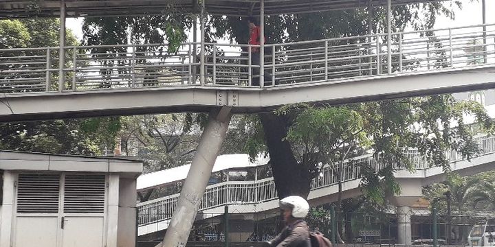 Tiang jembatan penyeberangan orang (JPO) di dekat RS Sumber Waras, Jakarta Barat, miring dan terlepas dari alas beton akibat ditabrak bus transjakarta,  Selasa (25/9/2018) pagi pukul 06.08 WIB.