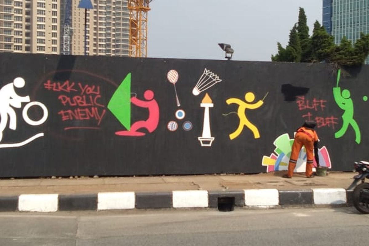 Petugas penanganan prasarana dan sarana umum (PPSU) Kelurahan Pondok Pinang membersihkan coretan-coretan yang mengotori mural Asian Games 2018 di perempatan Pondok Indah Mall, Jakarta Selatan, Rabu (25/7/2018).