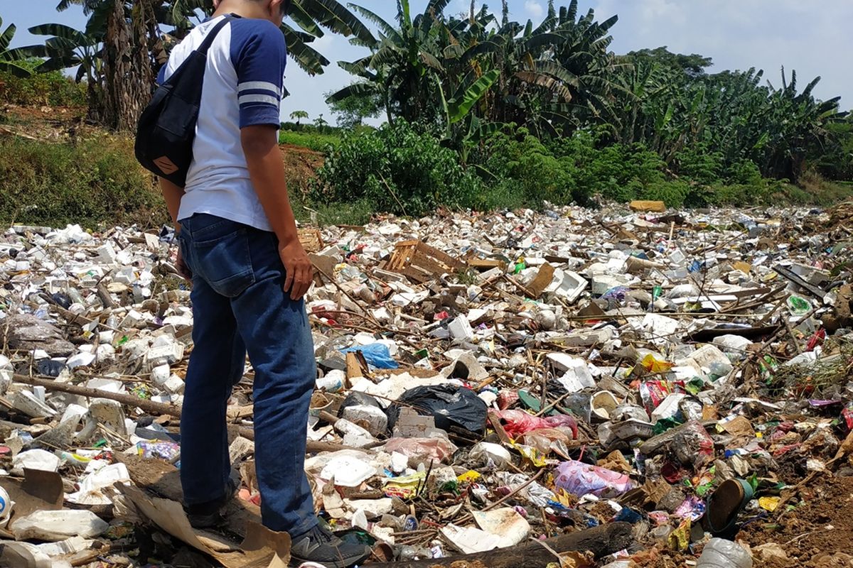 Warga berdiri di atas tumpukan sampah yang memenuhi aliran Kali Jambe di Desa Satriajaya, Tambun Utara, Kabupaten Bekasi, Rabu (30/10/2019) siang.
