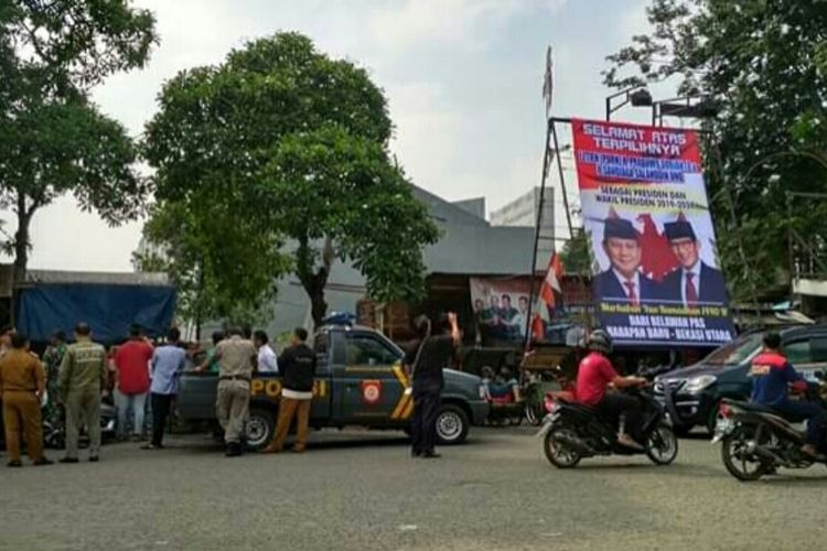 Tampak baliho ucapan kemenangan Prabowo-Sandiaga tengah diturunkan personel gabungan di wilayah Kota Bekasi, Senin (6/5/2019).