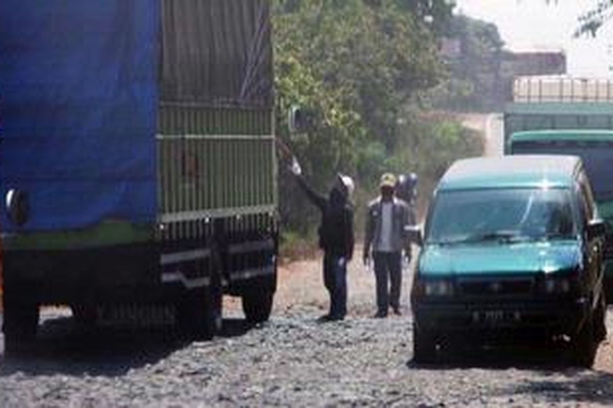 Kendaraan berjalan pelan saat melalui jaan rusak di jalur lintas pantai timur Sumatera di Kecamatan Way Jepara, Lampung Timur, Jumat (3/8/2012). Kondisi tersebut dimanfaatkan warga untuk "meminta" uang kepada sopir angkutan barang dan angkutan umum.   