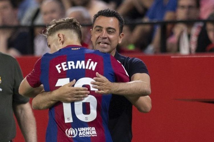 Fermin Lopez memeluk Xavi Hernandez usai mencetak gol dalam laga Sevilla vs Barcelona di Stadion Ramon Sanchez Pizjuan, Senin (27/5/2024) dini hari WIB. (Photo by JORGE GUERRERO / AFP)
