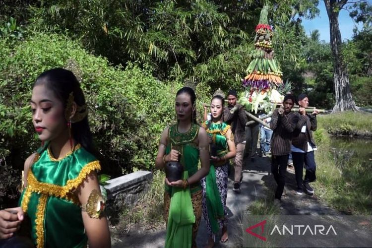 Warga desa membawa kendi atau tempat air diiringi gunungan hasil bumi dalam upacara dimulainya pengembangan objek wisat baru Dewi Pancuran di Desa Kiringan, Kabupaten Boyolali, Jawa Tengah, Kamis (25/8/2022).