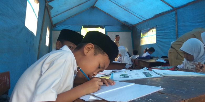 Seorang murid kelas 4 SD Kadupandak 2 berusaha fokus menerima pelajaran dari guru meski harus belajar di tenda darurat. Kegiatan belajar mengajar dialihkan ke tenda darurat karena ruang kelas rusak akibat pergerakan tanah di Dusun Sukamandi, Kecamatan Tambaksari, Kabupaten Ciamis.