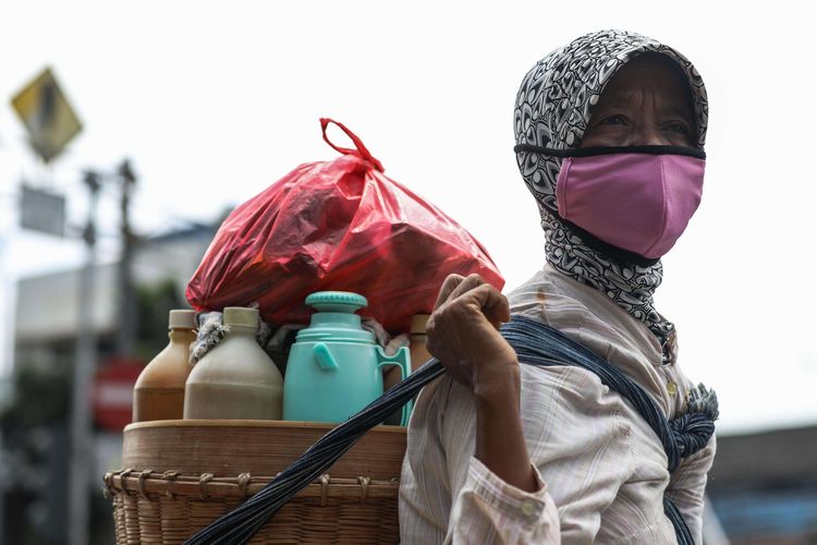 Penjual jamu menggunakan masker saat melewati jalan di kawasan Mampang Prapatan, Jakarta Selatan, Senin (6/4/2020). Kebijakan wajib masker itu  tertuang dalam Seruan Gubernur Daerah Khusus Ibu Kota Jakarta Nomor 9 Tahun 2020 Tentang Penggunaan Masker Untuk Mencegah Penularan Corona Virus Disease (Covid-19).