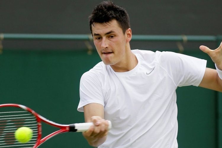 Petenis Australia, Bernard Tomic, memukul bola ke arah Sam Querrey dari Amerika Serikat, saat saling berhadapan di babak pertama Wimbledon, Selasa (25/6/2013).