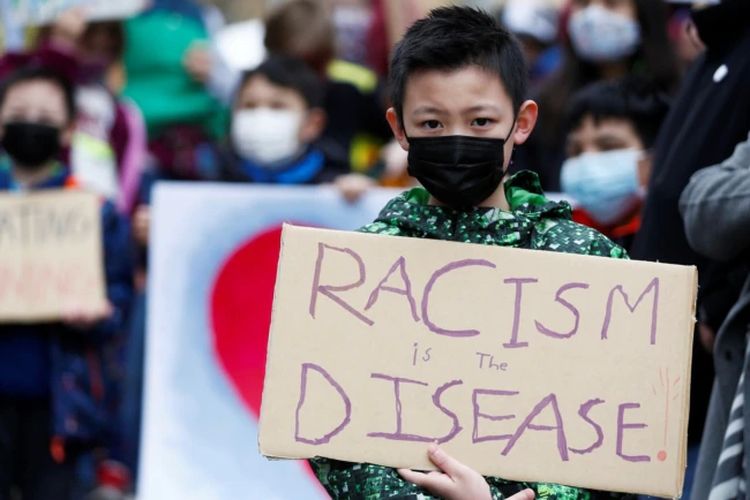 Ethan Yang, 11, memegang tanda bertuliskan rasisme adalah penyakit selama unjuk rasa Anak vs. Rasisme melawan kejahatan rasial anti-Asia di Hing Hay Park di Chinatown-International District of Seattle, Washington, AS, 20 Maret 2021.
