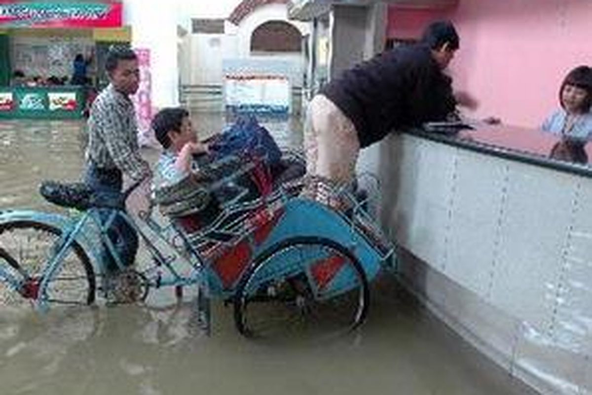 Beli Tiket dari Becak Calon penumpang terpaksa diantar dengan becak untuk membeli tiket kereta api di Stasiun Tawang, Semarang, Jawa Tengah, Selasa (19/2). Air setinggi antara 5 dan 20 cm di atas rel kereta api membuat jadwal keberangkatan lima kereta api ditunda