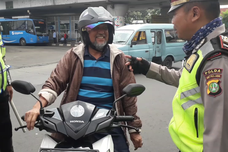 Seorang pengendara motor dihentikan polisi karena kedapatan merokok saat berkendara di kawasan Kampung Melayu, Senin (8/4/2019).