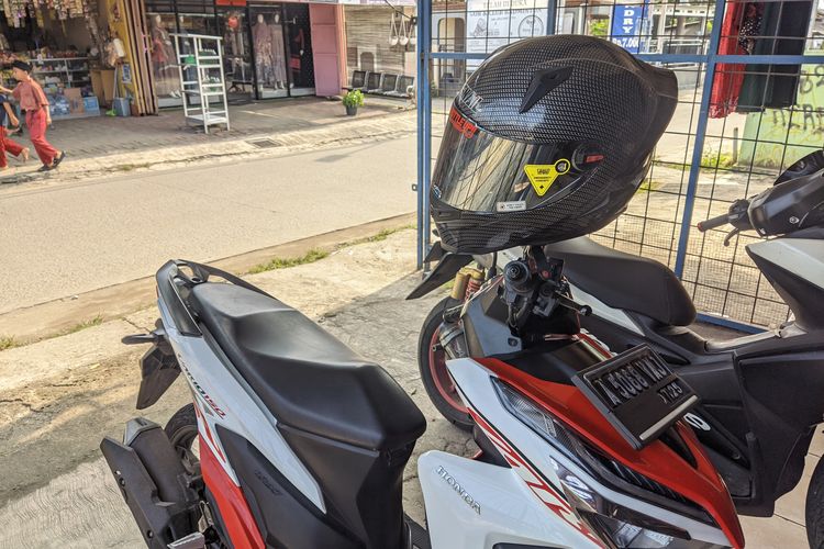 Ilustrasi Helm digantung di Spion Motor
