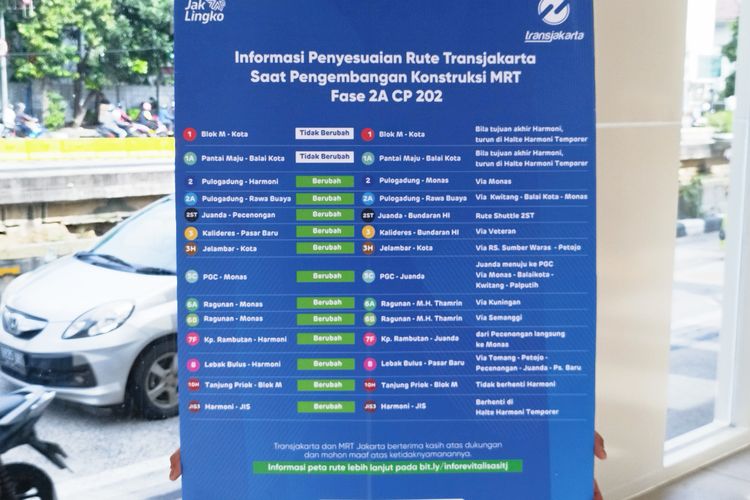 Petugas Transjakarta (TJ) bernama Randy membawa papan pengalihan rute bus imbas relokasi Halte Harmoni sementara, Senin (6/3/2023).