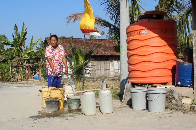 Warni (50), warga Dusun Marmoyo, Desa Marmoyo, Kecamatan Kabuh, Kabupaten Jombang, Jawa Timur, saat mengambil air di salah satu penampungan air di kampungnya, Rabu (26/6/2019). 