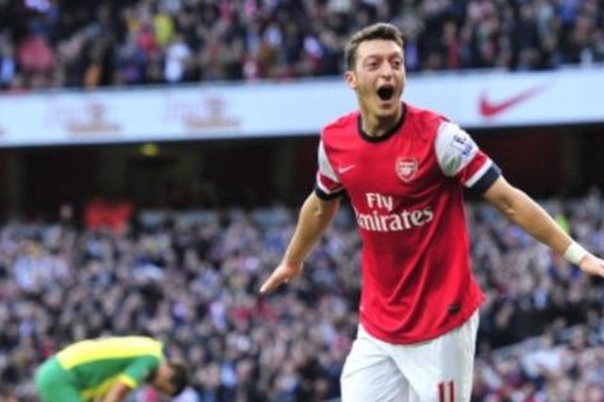 Gelandang Arsenal, Mesut Oezil (merah), merayakan gol yang dicetak ke gawang Norwich City dalam lanjutan Premier League, di Stadion Emirates, London, Sabtu (19/10/2013). Terkini, Mesut Oezil memutuskan pensiun dari dunia sepak bola.