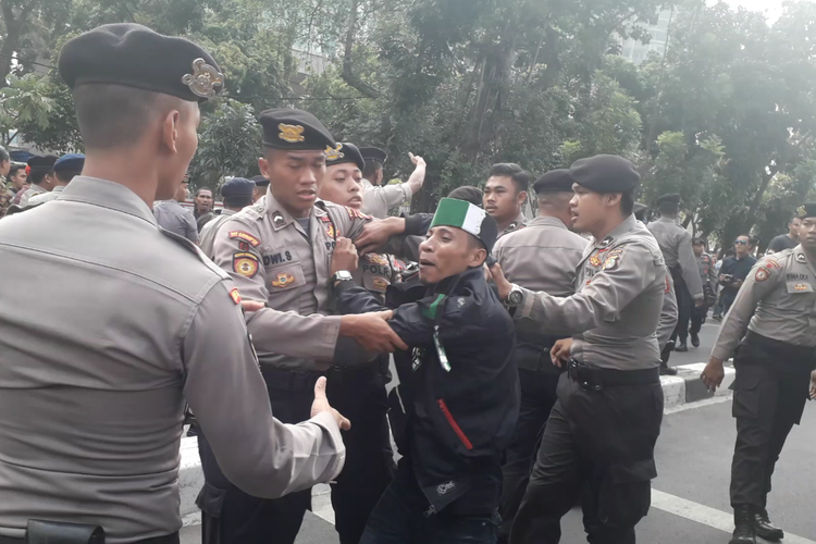 Petugas kepolisiam mengamankan seorang pengunjuk rasa beratribut HMI di depan Gedung Merah Putih KPK, Rabu (18/9/2019).