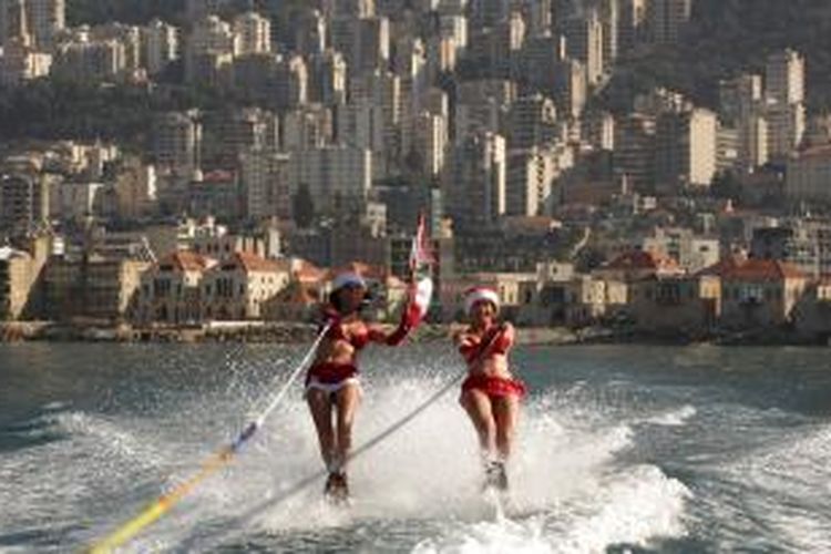 Beragam cara orang mengekspresikan sambutan pada Natal. Dua perempuan muda Lebanon, misalnya, mengekspresikannya dengan berselancar mengenakan modifikasi kostum Santa Claus, Selasa (24/12/2013).   