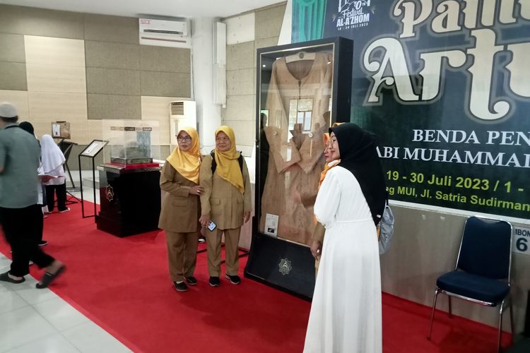 Pengunjung berfoto di samping jubah Nabi Muhammad SAW di pameran artefak nabi.