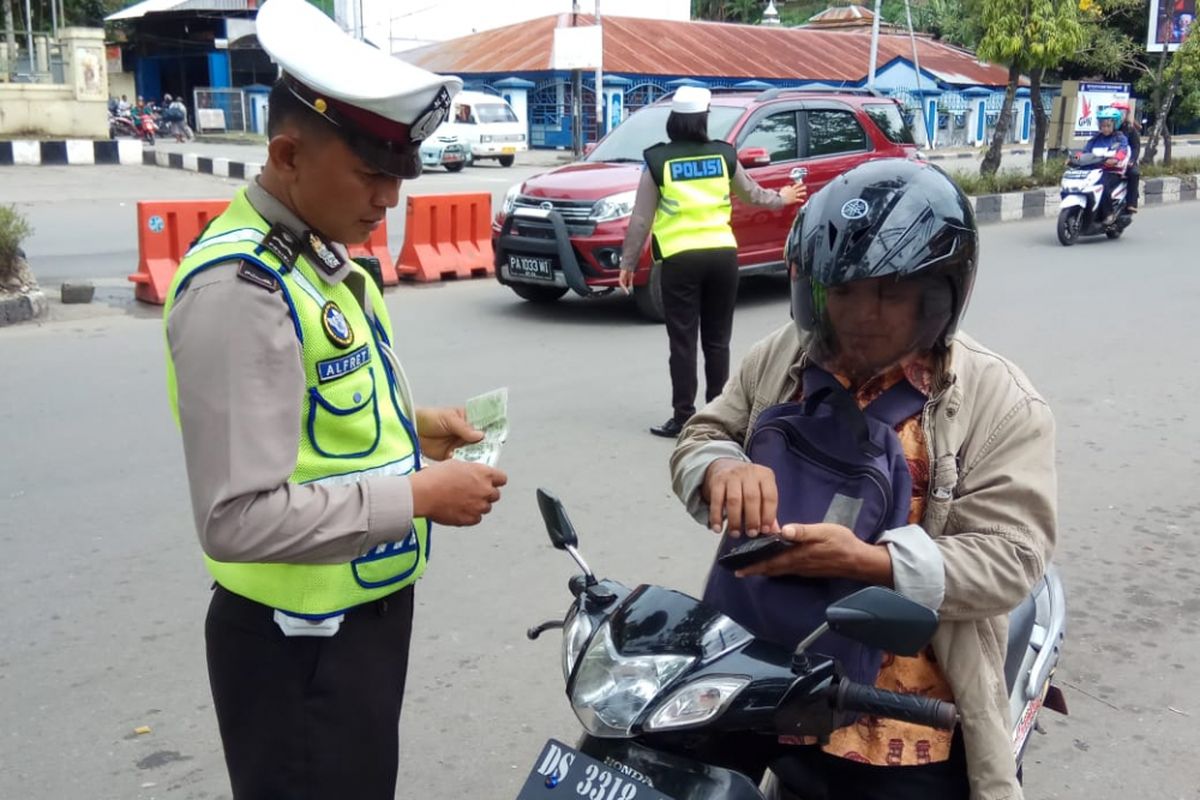 Seorang anggota lalu lintas saat memeriksa surat kendaraan dari pengendara sepeda motor saat Operasi Zebra Matoa 2018, di Papua. 
