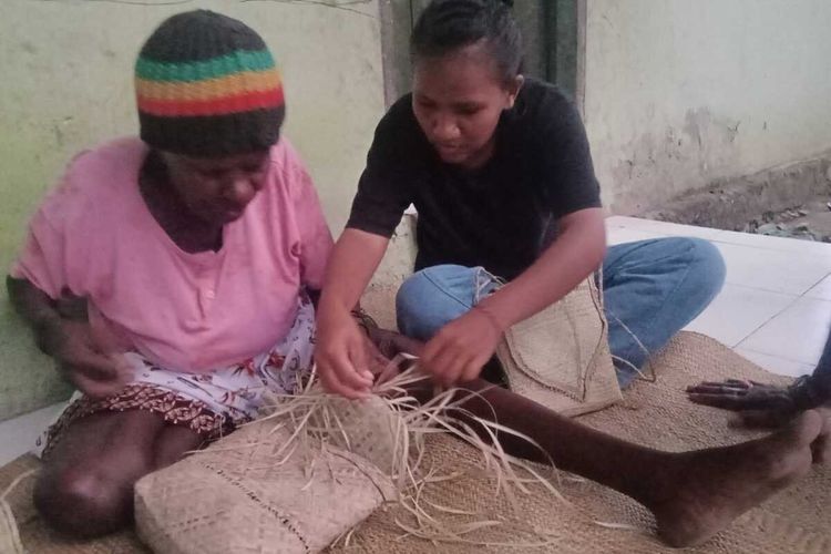 Bernadeta Natuapoka (82), saat mengajarkan Angelbertha Boi Duli mencoba membuat noken asli Suku Kamoro di depan rumahnya di SP 04, Distrik Wania, Kabupaten Mimika, Papua.