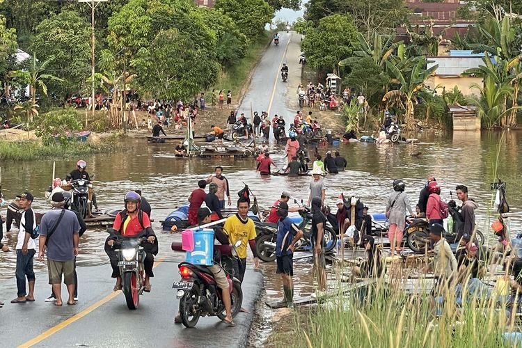 Sejumlah warga dan kendaraan memadati ruas jalan Sintang-Putussibau yang putus akibat terendam banjir di Kabupaten Sintang, Kalimantan Barat, Sabtu (13/11/2021). BPBD Kabupaten Sintang menyatakan banjir masih merendam beberapa kecamatan di daerah setempat, meski demikian banjir telah surut 10 hingga 15 sentimeter pada Jumat (12/11/2021) kemarin.