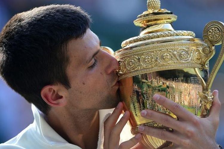 Petenis Serbia, Novak Djokovic, mencium trofi juara Wimbledon yang dia dapatkan setelah mengalahkan petenis Swiss, Roger Federer, pada partai final yang berlangsung di All England Tennis Club, London, Minggu (6/7/2014). Djokovic menang 6-7 (7), 6-4, 7-6 (4), 5-7, 6-4.