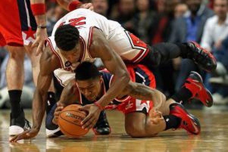 Pemain Chicago Bulls Jimmy Butler (atas) jatuh di atas pemain Wahisngton Wizards Bradley Beal pada laga kedua babak play-off Wilayah Timur di United Center, Selasa (22/4/2014).