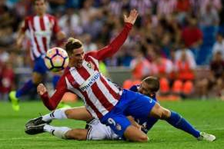 Striker Atletico Madrid, Fernando Torres, dijatuhkan pemain Alaves, Viktor Laguardia, saat kedua tim beradu di Vicente Calderon, Minggu (21/8/2016). 