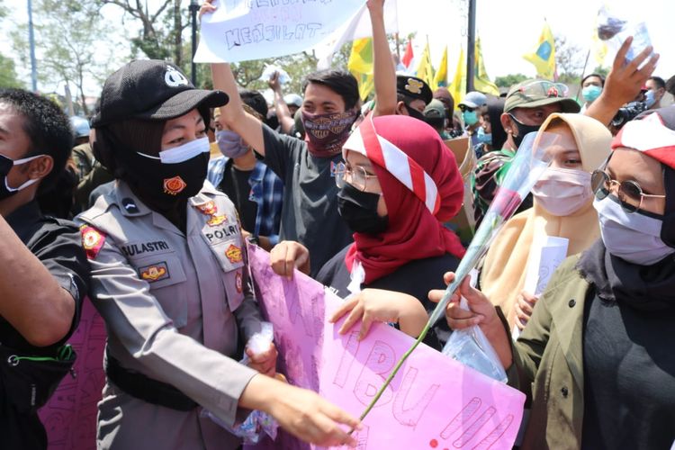Briptu Iti Sulastri saat membagikan bunga kepada masa aksi menolak undang-undang Omnibus Law di depan kantor DPRD Majalengka.