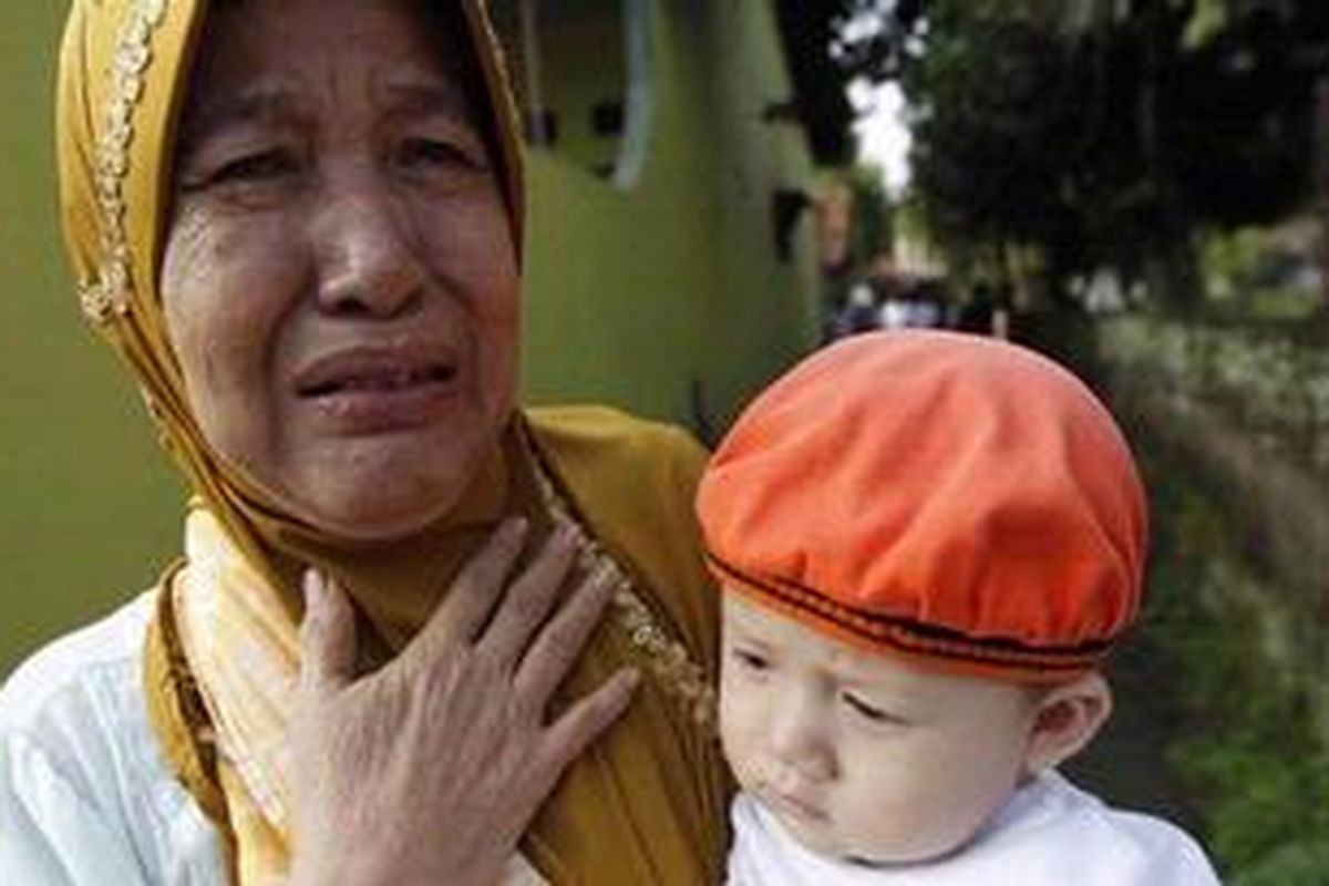 Samsiah (80) menangis sambil menggendong cucunya pasca-penyerbuan sekelompok massa ke desanya di Ciampea Udik RW 5, Kecamatan Ciampea, Kabupaten Bogor, Jawa Barat, Sabtu (2/10/2010). Dia bersama cucunya sempat sembunyi di bak mandi saat massa menyerbu dan merusak rumahnya. Massa menyerbu desa yang dihuni sekitar 500 jemaah Ahmadiyah, menghancurkan belasan rumah dan membakar dua rumah serta satu masjid. 