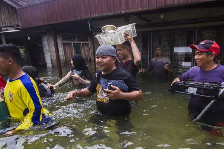Warga menyelamatkan barang dari rumah yang terendam banjir di Desa Banua Raya di Kabupaten Tanah Laut, Kalimantan Selatan, Senin (11/01).