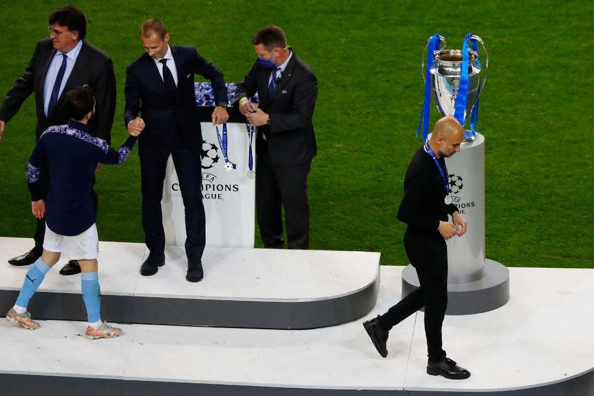 Pelatih Manchester City, Pep Guardiola, berjalan melewati trofi Liga Champions seusai kekalahan melawan Chelsea di laga final di Stadion Dragao, Porto, pada Minggu (30/5/2021) dini hari WIB.