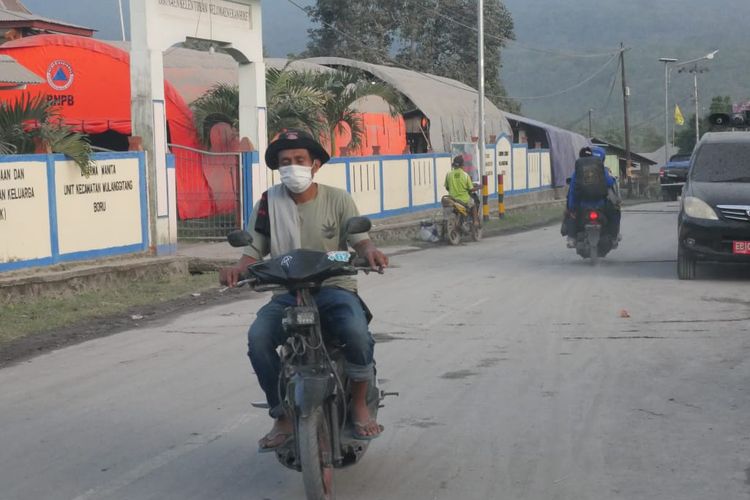 Seorang pengendara motor mengenakan masker untuk melindungi diri dari abu vulkanis Gunung Lewotobi Laki-laki, Selasa (2/1/2024). (Kompas.com/Serafinus Sandi)