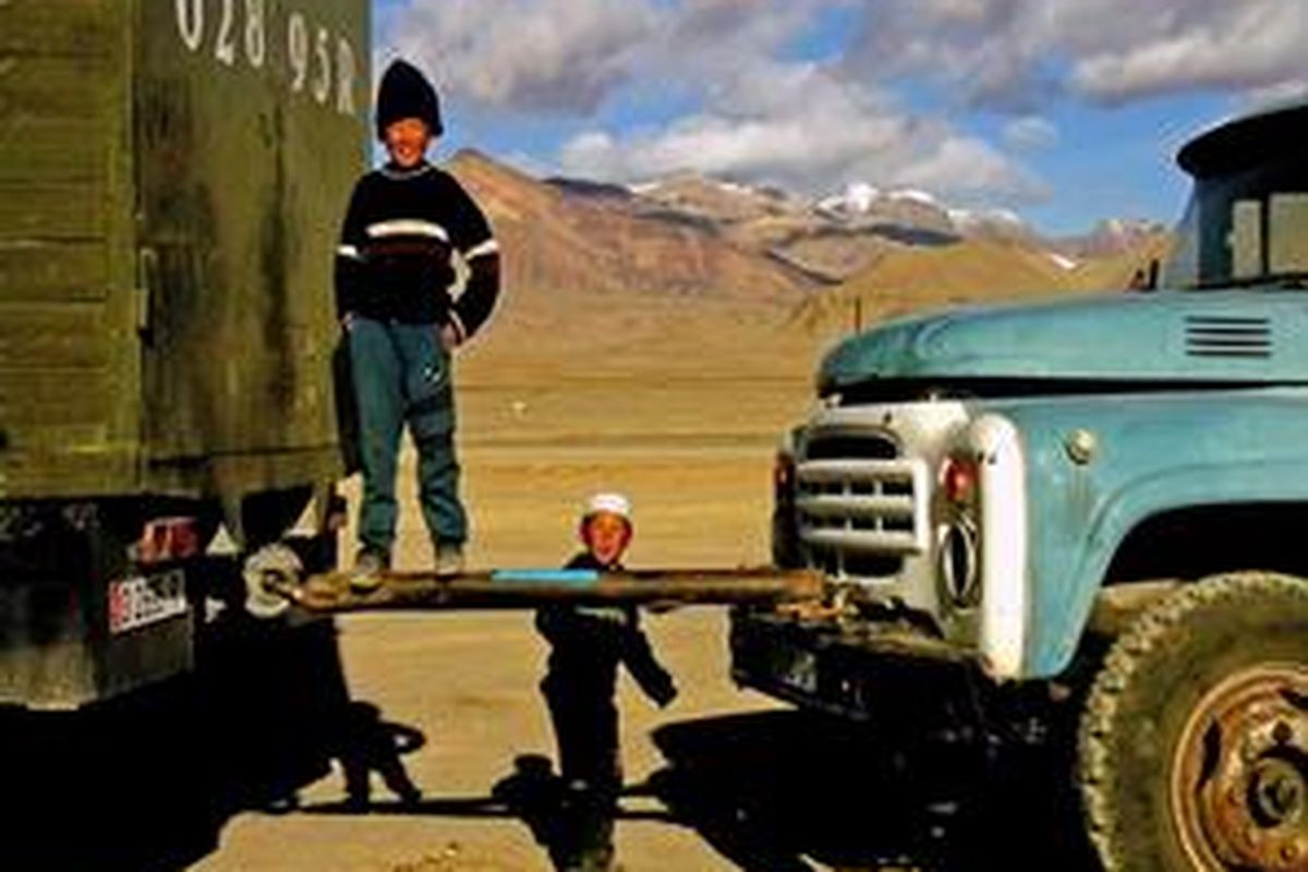 Anak-anak Kirghiz bermain di dekat truk Kamaz. 