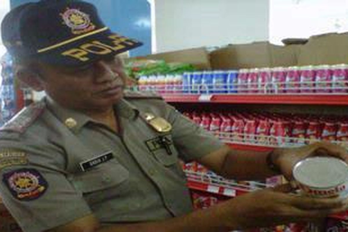 Seorang petugas Satpol.PP, Pemkab Kediri, Jawa Timur mengecek tanggal kedaluwarsa dalam razia makanan dan minuman di sebuah minimarket, Senin (22/8/2011).