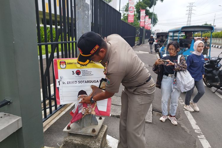 Satpol PP mencabut APK yang terpasang di tiang menggunakan kawat di kawasan Pasar Senen, Jakarta Pusat, Senin (12/2/2024).