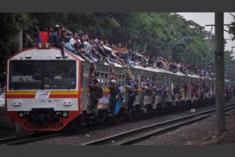 Kereta rangkaian listrik ekonomi tujuan Bogor dipenuhi penumpang yang duduk di atap dan bergelantungan di samping gerbong pada jam pulang kerja saat melintas di kawasan Tanjung Barat, Jakarta Selatan, Selasa (26/6/2012).